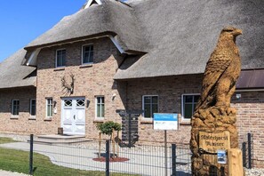 A brick building with a thatched roof, a wooden eagle sculpture, and a sign indicating the name 'Adlerhorst Kaiser'. - Holiday apartment with 3 bedrooms (Born a. Darß)