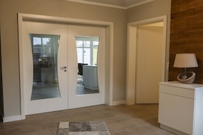 A room with a double door, a small cabinet, and a lamp on a side table. - Holiday apartment with 3 bedrooms (Born a. Darß)