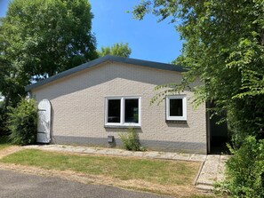 A single-story house with a brick exterior, a garage door, and two windows. - Zo03 Holiday Home/apartment With pet (Zoutelande)