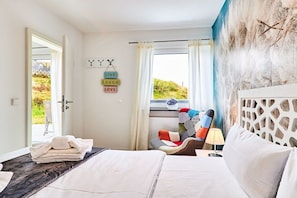 Een hotelkamer met een bed, een raam met gordijnen, een wand met decoratieve elementen en uitzicht op groen.