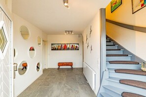 A hallway with a staircase, a bench, and a painting on the wall. - Holiday apartment in Hörnum with Wi-Fi (Hörnum)