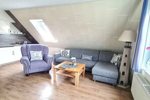 A modern living room with a sofa, armchair, and coffee table. - Holiday apartment with 1 bedroom (Norderney)