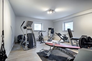 Ein Heimfitnessraum mit Cardiogeräten, Kurzhanteln und einer Trainingsbank.