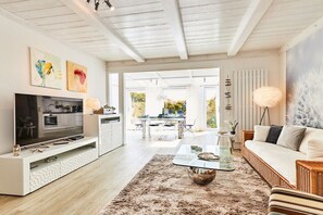 A modern living room with a flat-screen TV, a glass coffee table, and a sofa. - Holiday apartment in Hörnum with Wi-Fi (Hörnum)