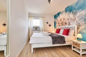 A bedroom with a bed, bedside table, and a wall with a decorative piece. - Holiday apartment in Hörnum with Wi-Fi (Hörnum)