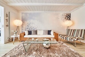 A modern living room with a sofa, a striped armchair, a glass coffee table, and two floor lamps. - Holiday apartment in Hörnum with Wi-Fi (Hörnum)