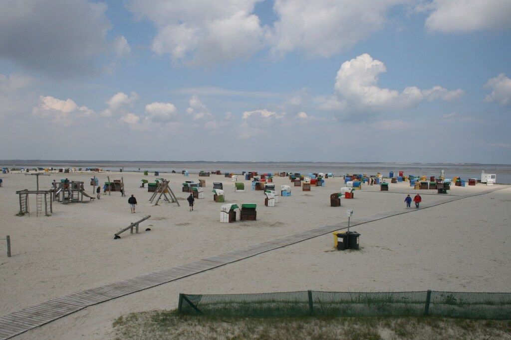 Una playa con una zona arenosa, un paseo de madera y varias estructuras coloridas.