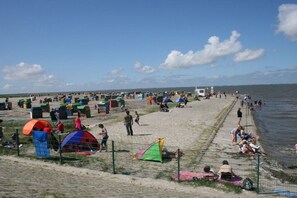 A beach with tents and people, a fence, and a body of water. - Paradise on the dike, House B (Neßmersiel)