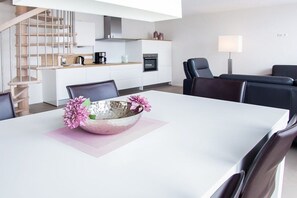 A modern kitchen with white cabinets, a stainless steel range hood, and a built-in oven. - Holiday apartment with 3 bedrooms (Norderney)
