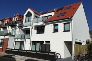 A multi-story residential building with balconies, a gated entrance, and bicycles parked outside. - Holiday apartment with 3 bedrooms (Norderney)