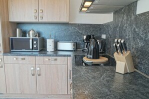 A modern kitchen with a microwave, toaster, coffee maker, and a knife block. - Küsters holiday apartment "Tina" (Hinte)