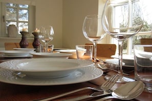 A dining table set with white plates, silverware, and wine glasses, with a window in the background. - Holiday apartment in Sylt with 2 bedrooms (Wenningstedt)