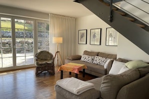 A living room with a sofa, a chair, a table, and a staircase. - Apartment on the east side (Mönchgut, OT Gager)