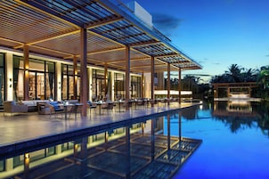 Un moderno comedor al aire libre con piscina, que incluye un área de estar cubierta y una vista despejada de la piscina.