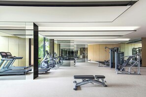 Un gimnasio moderno con diversos equipos de ejercicio, incluyendo cintas de correr, elípticas y máquinas de pesas.