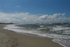 A beach with waves, a clear sky, and a distant shoreline. - Holiday apartment with 2 bedrooms (Norderney)