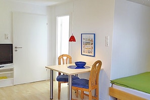 A room with a dining table, chairs, a television, and a framed picture on the wall. - Holiday apartment with 2 bedrooms (Norderney)