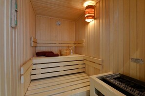 A sauna with wooden benches, a towel, and a heater. - Holiday apartment with 2 bedrooms (Sassnitz)