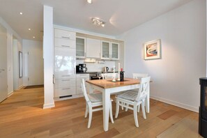 Eine moderne Küche mit weißen Schränken, einem Holztisch und weißen Stühlen.