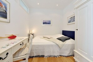 A bedroom with a bed, bedside table, and a desk with a chair. - Holiday apartment with 2 bedrooms (Sassnitz)