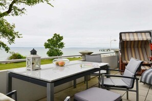 An outdoor patio with a table, chairs, a lantern, and a view of the water. - Holiday apartment with 2 bedrooms (Sassnitz)