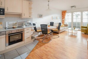 A modern kitchen with a dining area, featuring a central island, chairs, and a sofa. - Holiday apartment in Juist with swimming pool (Juist)