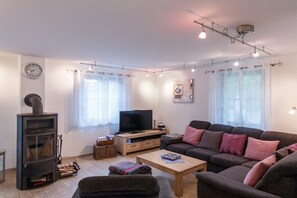 A living room with a sofa set, a television, a fireplace, and a clock on the wall. - Holiday home with 3 bedrooms (born an der darss)
