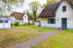 Ein traditionelles Dorf mit reetgedeckten Häusern, einem gepflasterten Weg und einem kleinen Schuppen.