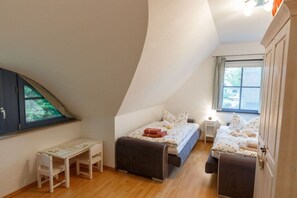 A bedroom with a sloped ceiling, two beds, a desk, and a window. - Holiday home with 3 bedrooms (born an der darss)