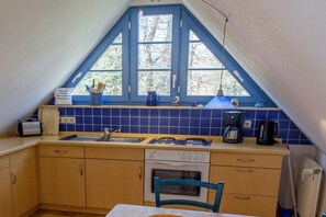A small kitchen with a window, a sink, a stove, and a dishwasher. - Sonnenhof Top Floor D5 (Prerow)