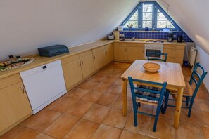Eine kompakte Küche mit Geschirrspüler, einem Esstisch mit Stühlen und einem Fenster über der Spüle.