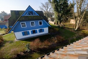 Ein zweistöckiges Haus mit einem steilen Satteldach, einer kleinen Veranda und einem gepflegten Rasen.