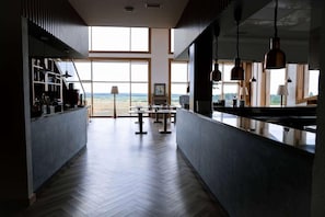 A spacious kitchen with a view of the beach, large windows, and modern pendant lighting. - Wyndham Residences Aqkol (Astana)