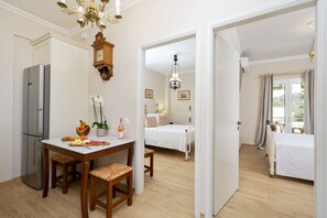 A hotel room with a dining area, a bed, a clock, and a view of the outdoors. - Venti Di Paxos 1 | Two-Bedroom Apartment, Apartment (Paxoi)