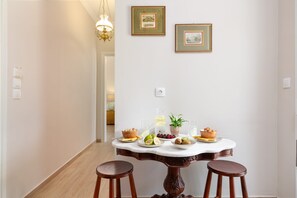 A dining area with a marble table, two wooden stools, and a chandelier. - Venti Di Paxos 2 | One -Bedroom Apartment, Apartment (Paxoi)