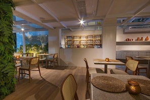 A restaurant interior with tables and chairs, a bar area, and a view of the outdoors. - Janga Boutique Hotel (Maragogi)