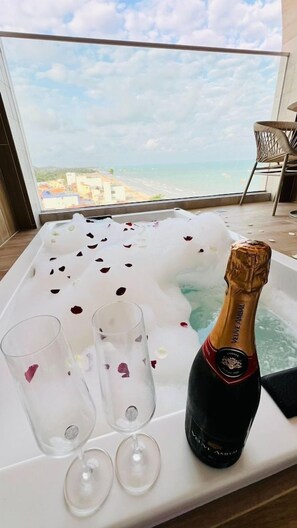 Ein Zimmer mit Blick auf den Strand, eine mit Wasser und Rosenblättern gefüllte Badewanne, zwei Gläser und eine Flasche Champagner.