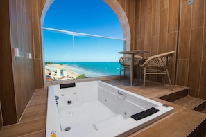 Ein modernes Badezimmer mit einer großen Badewanne, Holzwänden und Blick auf den Strand.