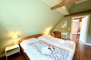 A bedroom with two beds, a nightstand, a lamp, a chair, and a mirror on the wall. - Old Registry Office Large Apartment (Oldsum)