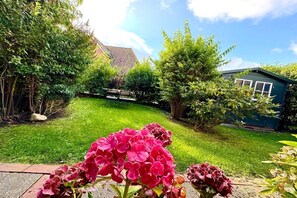 A garden with a lawn, a wooden fence, and a house with a sloped roof. - Old Registry Office Large Apartment (Oldsum)