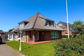 A two-story house with a sloped roof, a front porch, and a well-maintained lawn. - Hansen Grevelingstieg 16 (Nieblum)