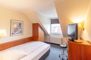 A hotel room with a bed, a desk with a television, a chair, a radiator, and a window. - Sunday Hotel Leipzig Südvorstadt (Markgraf) - Standard Single Room (Leipzig)