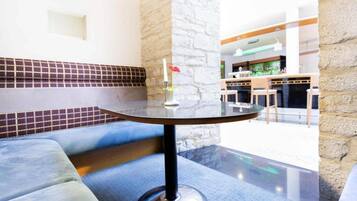 Een moderne zithoek met een ronde tafel, zachte zitplaatsen en een decoratieve vaas.