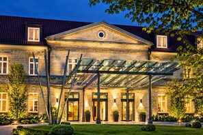 A large stone building with a glass-covered entrance and a well-lit facade. - Sunday Hotel Hildesheim Zentrum - Standard Double room (Hildesheim)