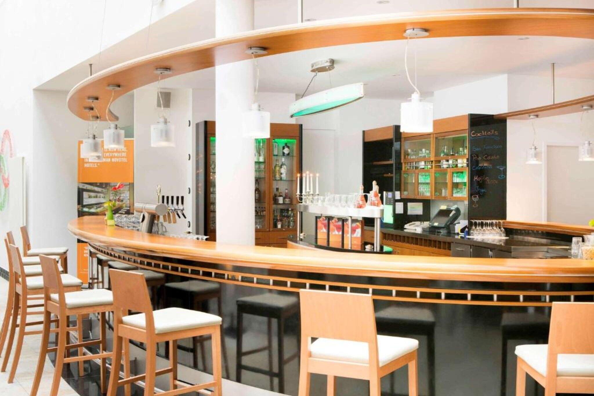 A modern bar area with a curved counter, bar stools, and a menu board.