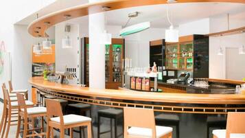 A modern bar area with a curved counter, bar stools, and a menu board.
