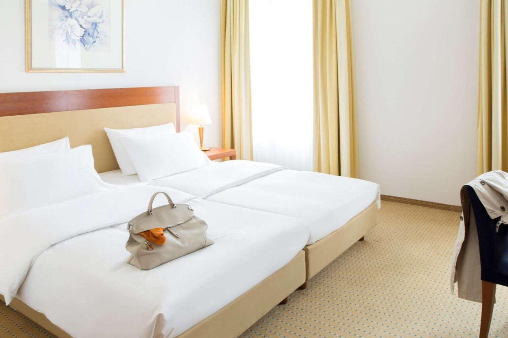 A hotel room with a large bed, a nightstand, a lamp, and a framed picture on the wall.