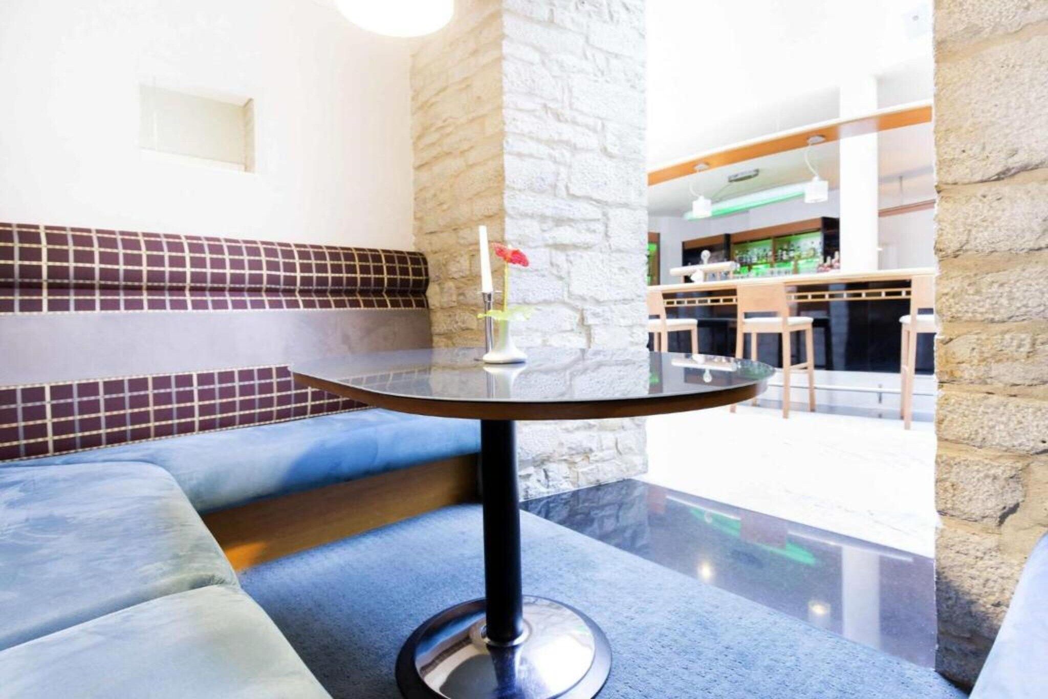 Un área de descanso moderna con una mesa redonda, asientos acolchados y un jarrón decorativo.