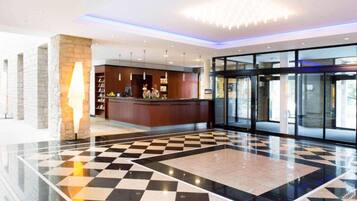 Eine Hotelhalle mit Schachbrettmuster-Boden, einer Rezeption und einer Drehtür.