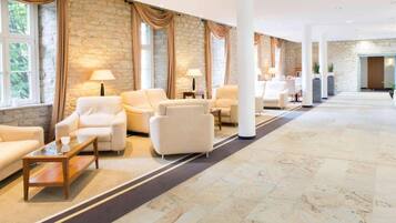 A hotel lobby with a row of sofas, a coffee table, and a stone wall.